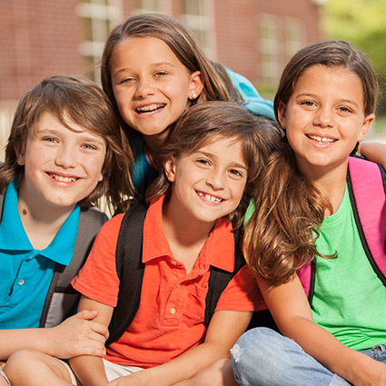 a group of smiling kids sitting outside school