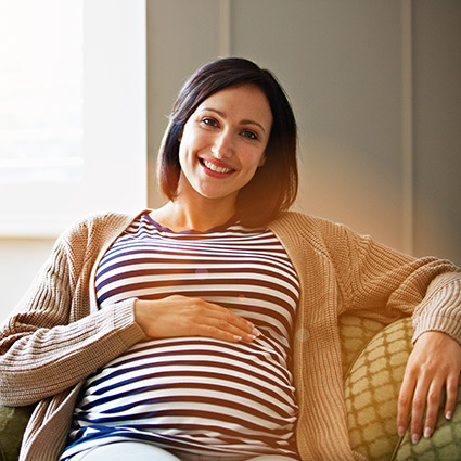 Smiling pregnant woman sitting on a couch