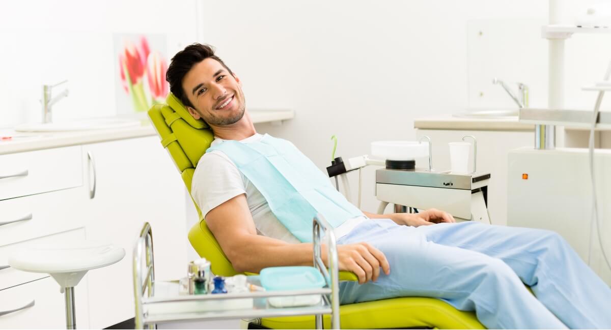 Male patient sitting on green dental chair