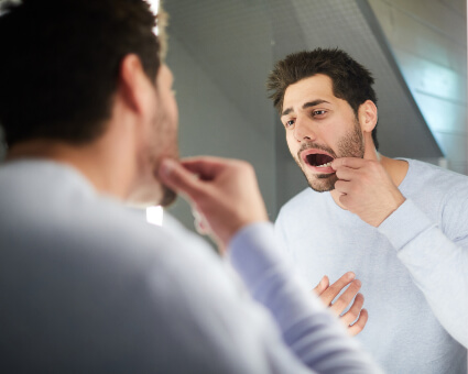 Man looking at mirror inspecting gums