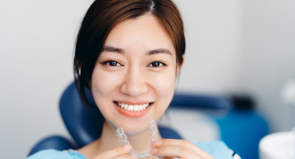 Smiling woman holding Invisalign