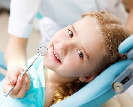 Smiling young girl sitting on dental chair