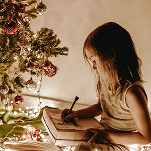 child colouring near a christmas tree