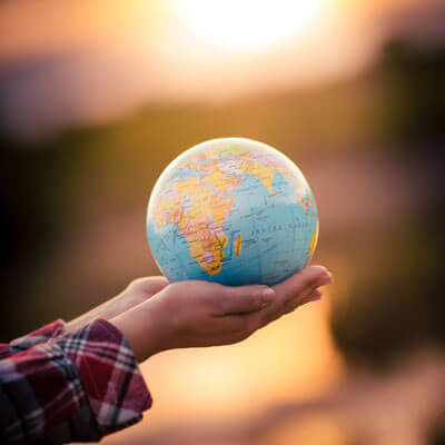 Woman holding globe in the sunset