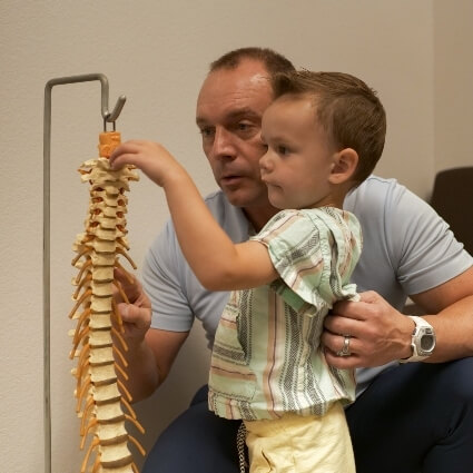 chiropractor discussing spine model with pediatric patient