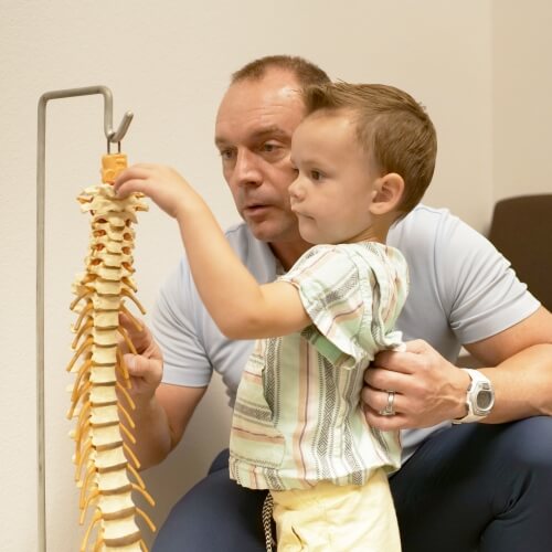 Dr. Roderick of Pro Active Chiropractic and Sports Medicine discussing spine model with pediatric patient
