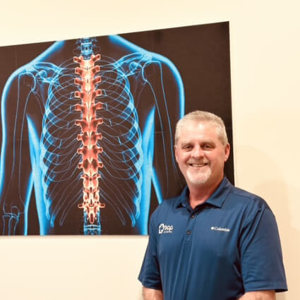Madison Chiropractor Dr. Chris Hoover standing by spine illustration