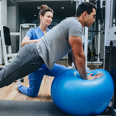 Man exercising assisted by physical therapist