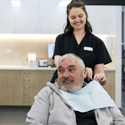 Staff putting bib on male patient