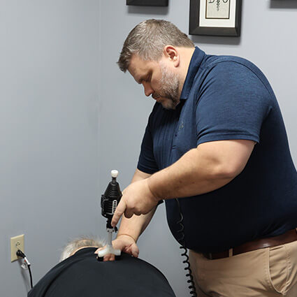 Dr Nathan adjusting patients back using a tool