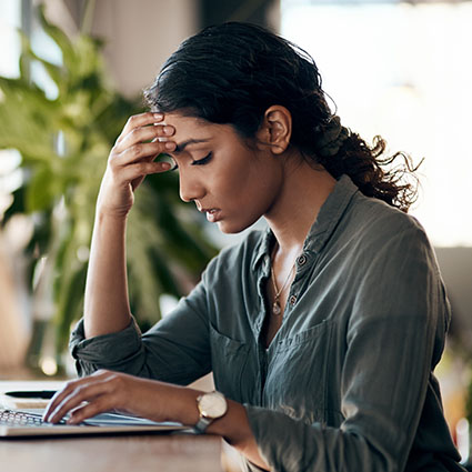 Woman with a headache working at a laptop