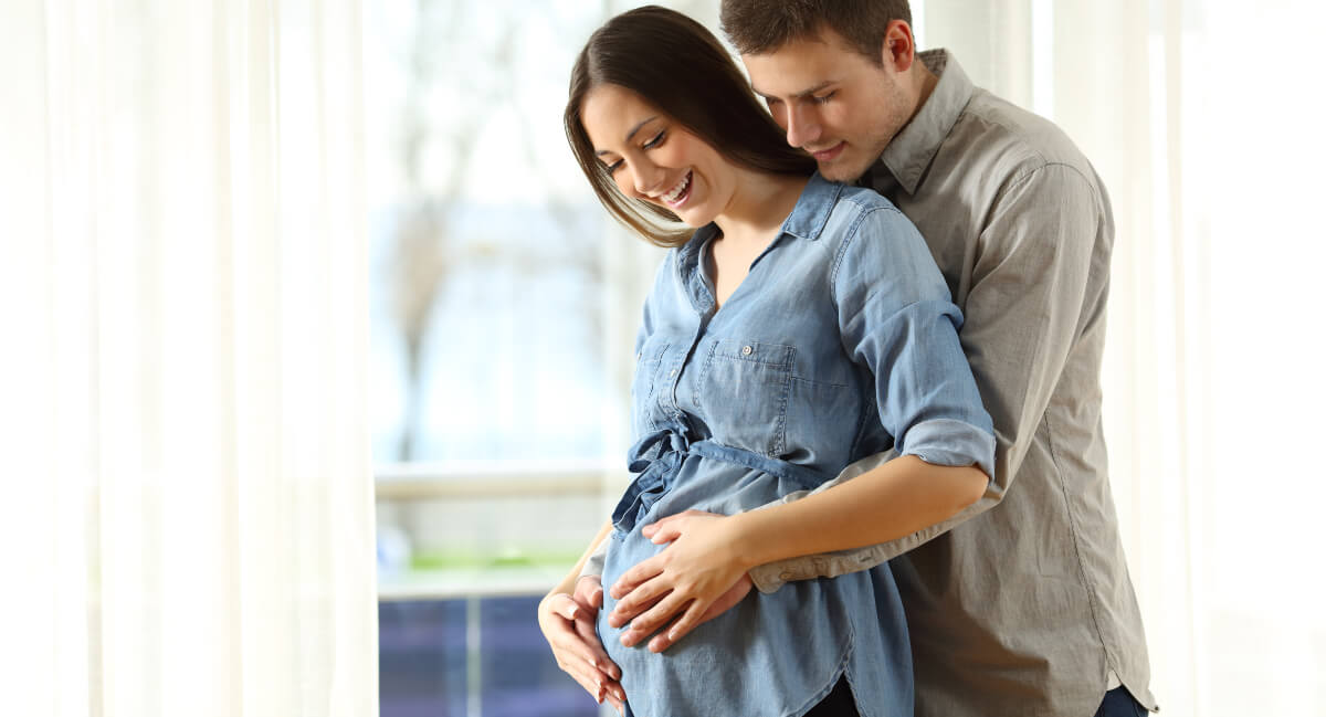Pregnant woman embraced by husband