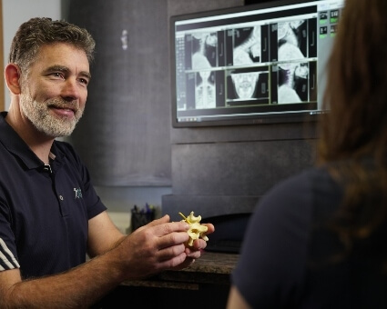 Chiropractor discussing spine model with patient