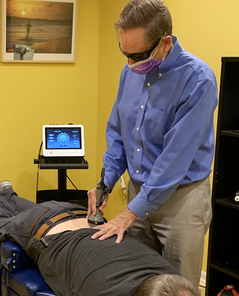 Dr. Jeff using laser on patient's back