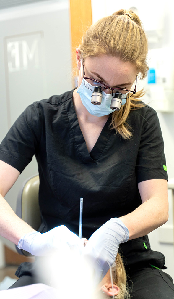 Dentist with magnifying glasses working on patients teeth