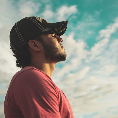 man with closed eyes looking at the sky