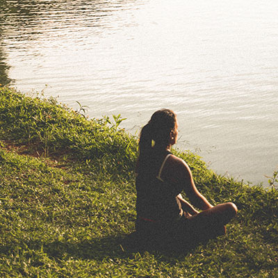 woman sitting relaxing next to a lake