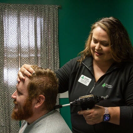 Dr Laura adjusting patients neck with tool