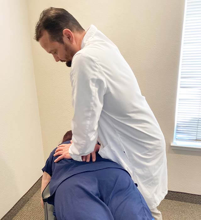 Dr. Joshua with patient in chiropractor bed
