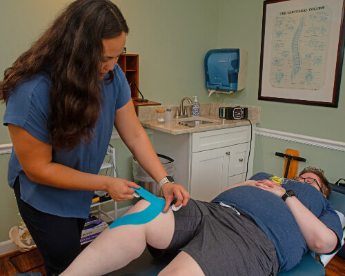 Chiropractor taping patients knee