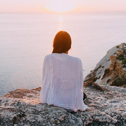 woman relaxing on rocks during a sunset