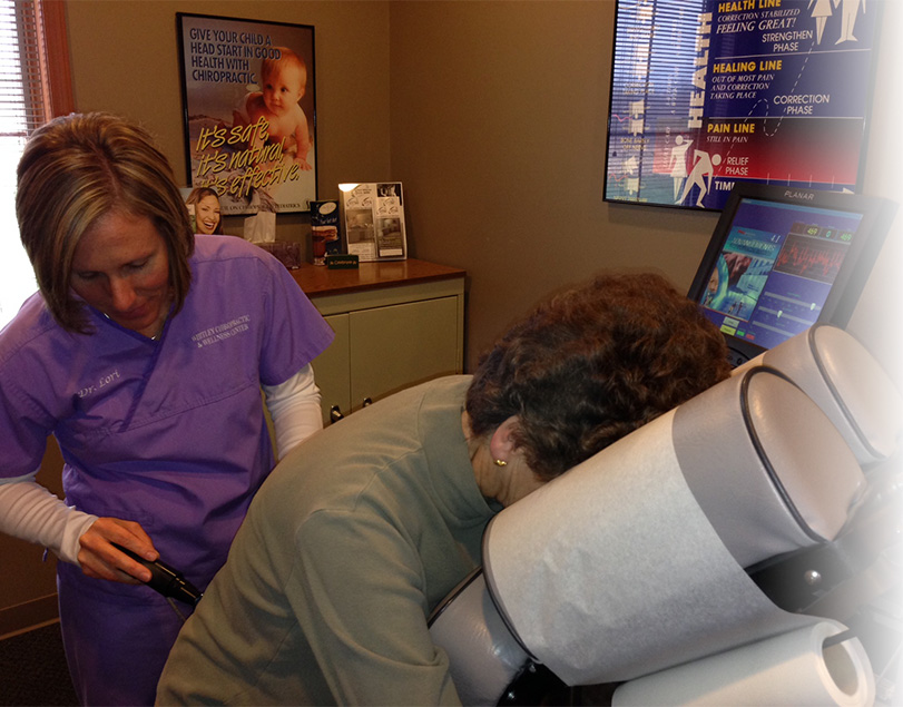 Chiropractor using activator on woman's back