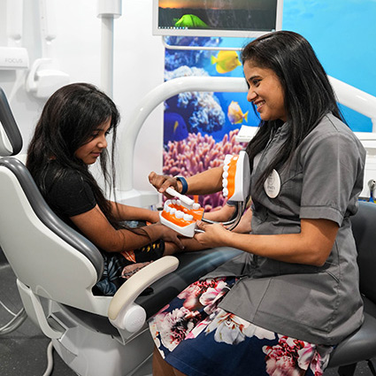 staff showing child a dental model