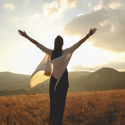 woman hands raised mountain view sunset