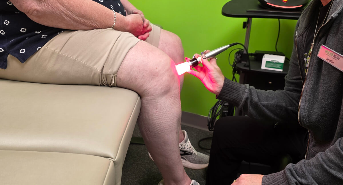 Denver chiropractor using laser therapy on patient's knee