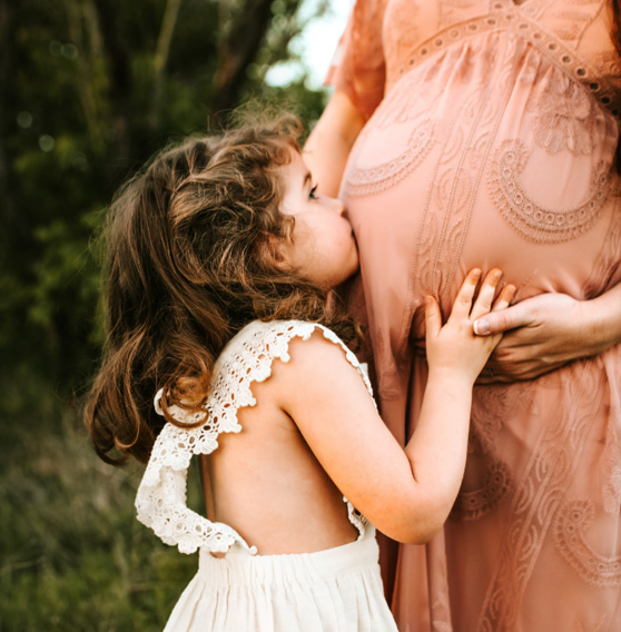 girl kissing moms pregnant belly