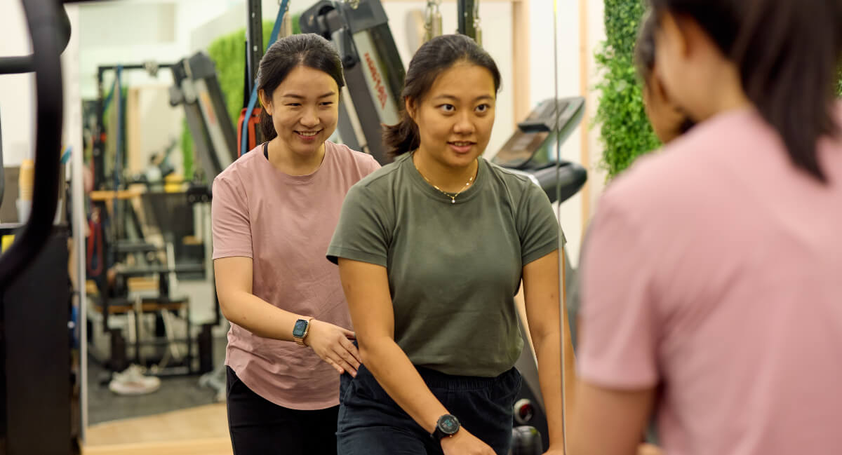 Pilates instructor and patient in front of mirror