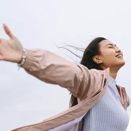 smiling-woman-in-pink-jacket-with-arms-outstretched-sq