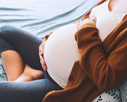 pregnant person sitting on bed