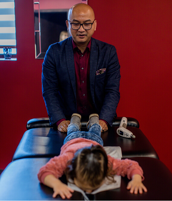 Chiropractor with young patient on adjusting table