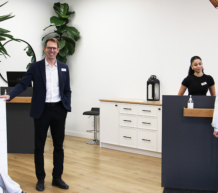 Chiropractic team standing in office with welcoming smiles