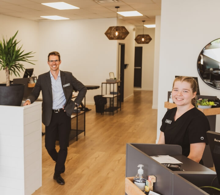 Chiropractic team standing in office with welcoming smiles