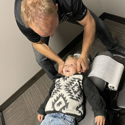 Dr. Johnson adjusting a smiling toddler's neck.