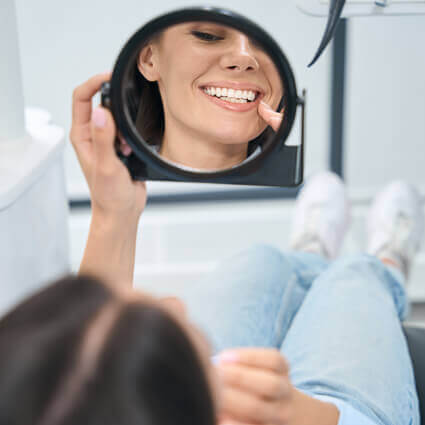 woman-inspecting-teeth-in-dentists-mirror-sq