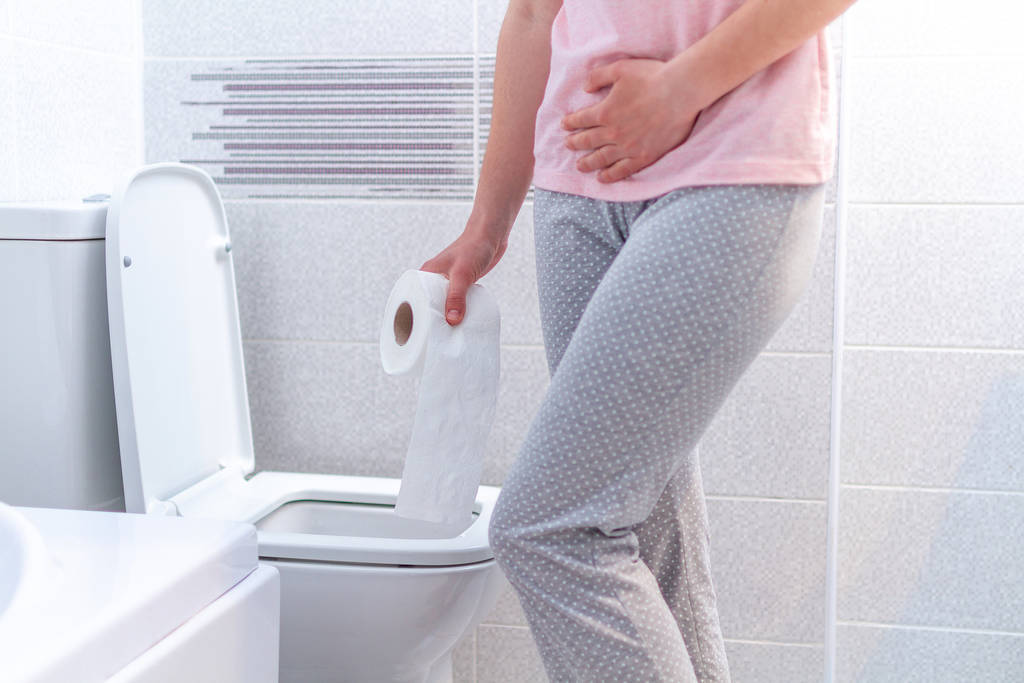 Woman holding a paper roll and suffering from diarrhea, constipa