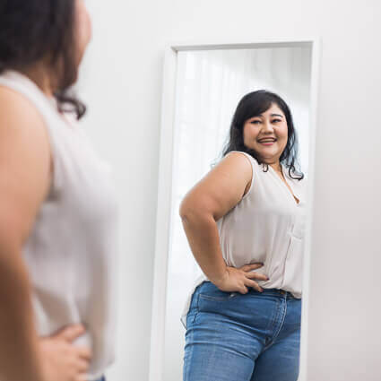 woman in white shirt cmiling and looking in mirror