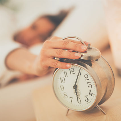 Woman reaching for alarm clock