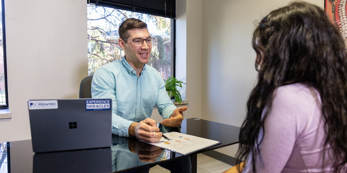 Dr. Jon Mudlaff speaking with a new patient at his desk.