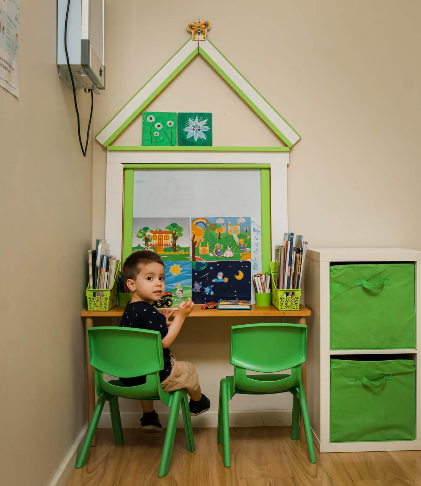A child sitting at a desk in a play area.