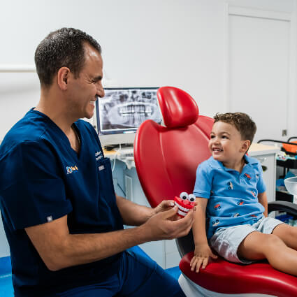 Dr Felipe laughing with child in dental chair