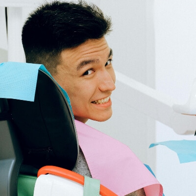 man in dental chair looking over shoulder and smiling