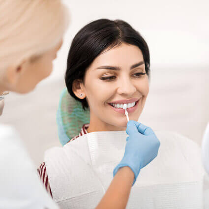 woman-observes-teeth-while-dentist-paints-on-whitener-sq