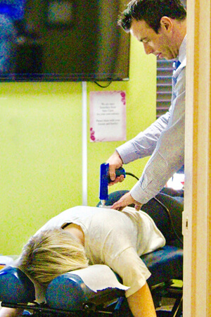Patient being adjusted by chiropractor with an instrument