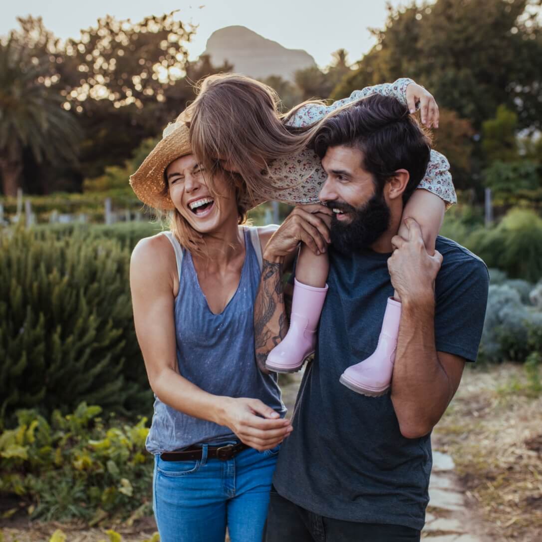 A mom, dad, and daughter taking a walk and laughing.