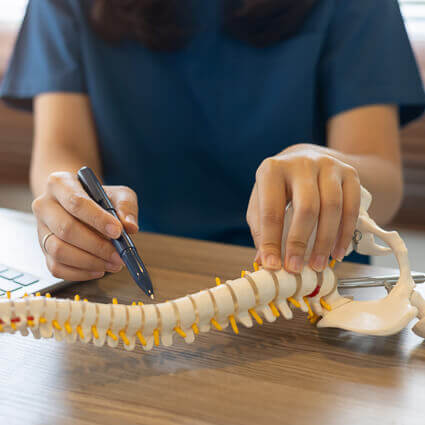 femail doctor with spine on desk pointing with pen