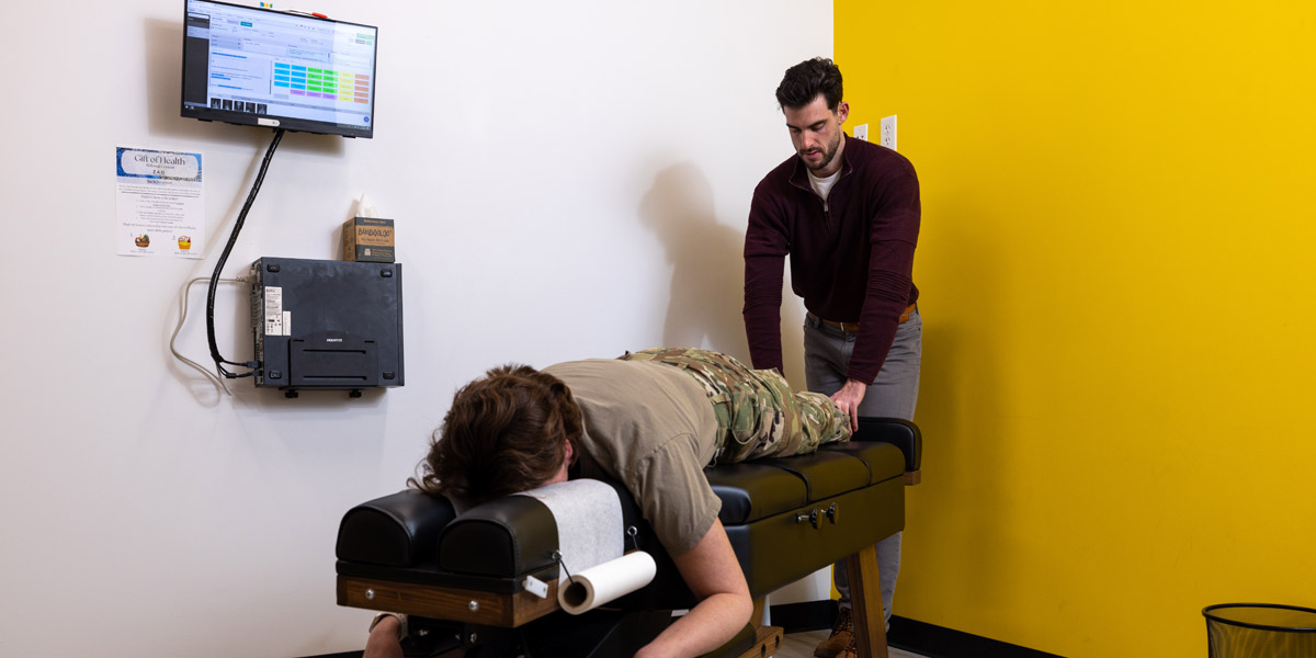 Dr. Dylan adjusting a woman in fatigues